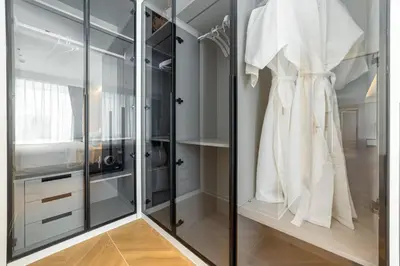 a walk in closet with glass doors and a white robe at Kora Beach Resort 3 bedroom By Ere D118 in Ko Kala