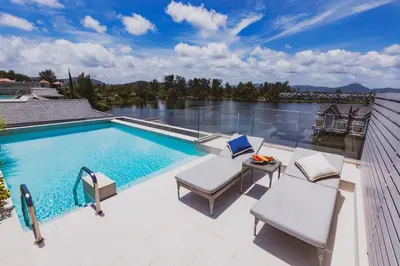 a swimming pool with two chairs and a table on a patio at Luxury Angsana Residence in Bang Tao Beach