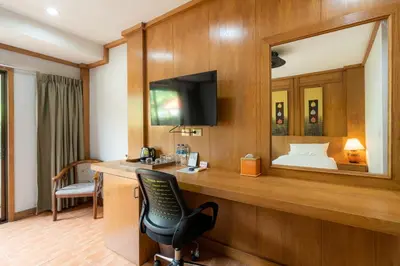 a hotel room with a desk with a chair and a bed at Chabana Resort Bang-tao Beach Phuket- SHA Extra Plus in Bang Tao Beach