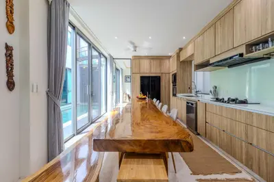 a large wooden table in a kitchen with a large window at V257 Spacious 5BR Villa Waterfall Pool Movie Room in Rawai Beach