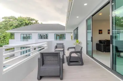 a balcony with chairs and tables on a house at V258 2 Villas 2 Kitchens 2 Livingrooms Huge Pool in Rawai Beach