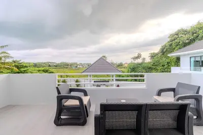 a patio with chairs and tables on a balcony at V258 2 Villas 2 Kitchens 2 Livingrooms Huge Pool in Rawai Beach