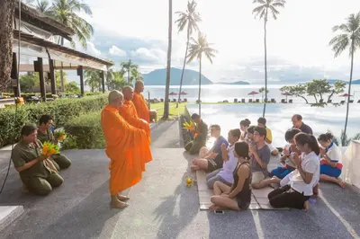 a group of monks standing next to a group of children at The Vijitt Resort - Deluxe Beachfront Villa in Ban Saiyuan (1)