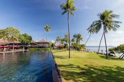 a pool at a resort with palm trees and the ocean at The Vijitt - Deluxe Seaview Villa in Ban Saiyuan (1)
