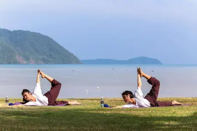 a group of people doing yoga on the grass by the water at The Vijitt - Deluxe Seaview Villa in Ban Saiyuan (1)