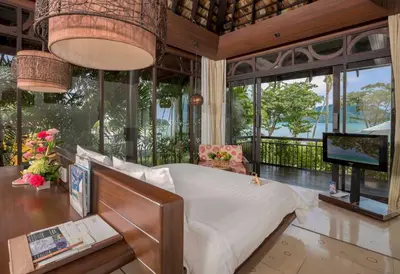 a bedroom with a bed and a tv and windows at The Vijitt - Deluxe Seaview Villa in Ban Saiyuan (1)