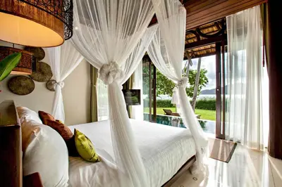 a bedroom with a bed with white curtains and a window at The Vijitt Resort - Vijitt Pool Villa in Ban Saiyuan (1)