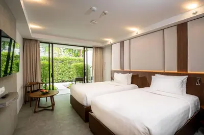 a hotel room with two beds and a window at Dewa Phuket - Deluxe Garden in Nai Yang Beach
