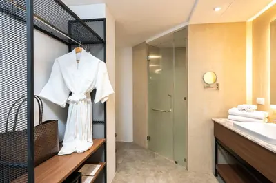 a bathroom with a white robe hanging on a rack at Dewa Phuket - Deluxe Garden in Nai Yang Beach