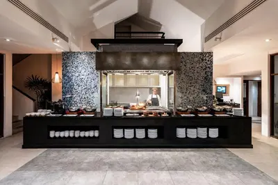 a man standing behind a counter in a restaurant at Naiyang Villa in Nai Yang Beach
