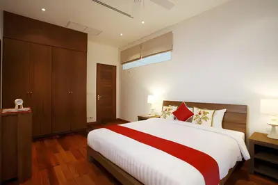 a bedroom with a large white bed with red accents at Sea View Pool Villa Grand Kamala Falls in Kamala Beach