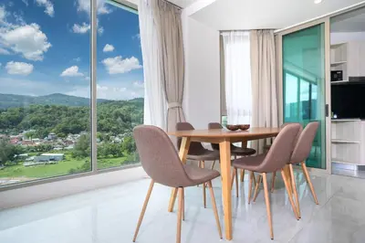 a dining room with a table and chairs and a large window at Elegant 2BR Oceanview Condo Oceana C73 - 5 min walk Kamala Beach in Kamala Beach