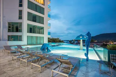 a hotel patio with chairs and a swimming pool at Elegant 2BR Oceanview Condo Oceana C73 - 5 min walk Kamala Beach in Kamala Beach