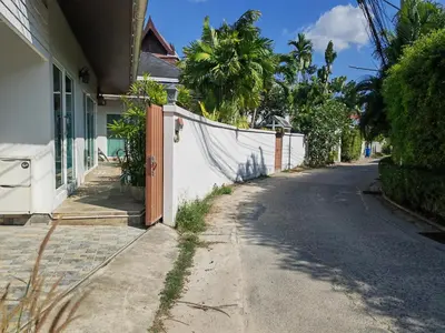 an empty street next to a house with a fence at Private Tropical Villa 2bdr Bangtao beach in Laguna Phuket