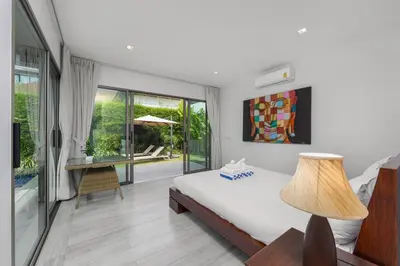 a bedroom with a bed and a table with a lamp at Villa Mauri – Modern 3BR Villa with Private Pool in Kata Beach