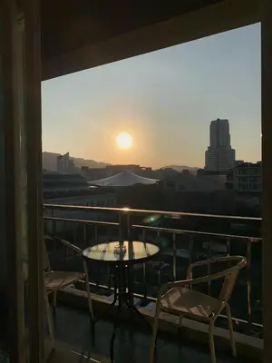 a table and chairs on a balcony with the sunset at Doze Bangla in Patong Beach
