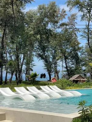 a row of white chairs in a swimming pool at Kora Beach Studio in Layan Beach