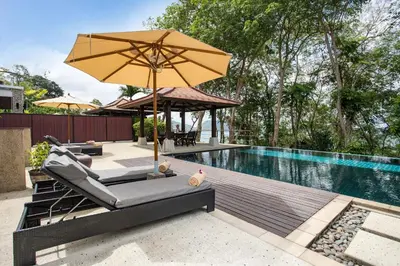 an umbrella and lounge chairs next to a swimming pool at 5 BR Villa Kalim 5 Private Pool with Seaview in Patong Beach