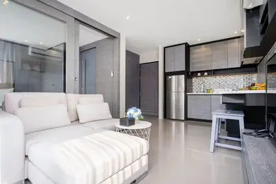 a living room with a white couch and a kitchen at Tropics Kamala CTG P615 - Corner 1 BR Apt Mountain view in Kamala Beach