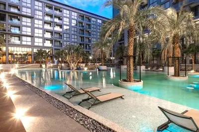 a swimming pool with chairs and palm trees in a building at Tropics Kamala CTG P615 - Corner 1 BR Apt Mountain view in Kamala Beach