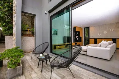 a living room with two chairs and a couch at Nature-Inspired 2BR Duplex P12 with pool and gym in Kamala Beach