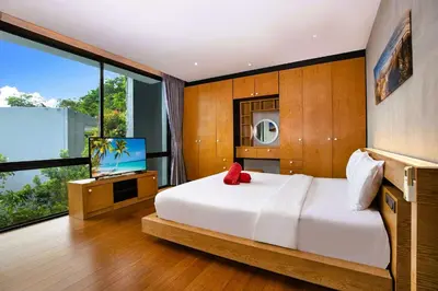 a bedroom with a large white bed and a television at Nature-Inspired 2BR Duplex P12 with pool and gym in Kamala Beach