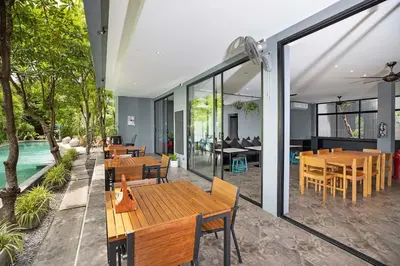 a patio with tables and chairs and a pool at Nature-Inspired 2BR Duplex P12 with pool and gym in Kamala Beach