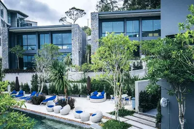 a building with a courtyard with blue chairs and trees at Nature-Inspired 2BR Duplex P12 with pool and gym in Kamala Beach