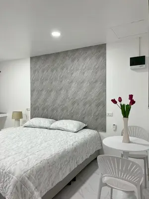 a bedroom with a bed and a vase of flowers on a table at Nur Nur Residence and villa in Surin Beach