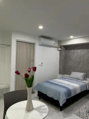 a bedroom with a bed and a vase with flowers on a table at Nur Nur Residence and villa in Surin Beach