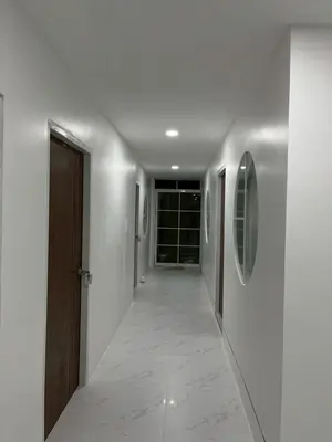 a hallway with white walls and a wooden door at Nur Nur Residence and villa in Surin Beach