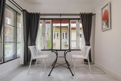a dining room with a table and chairs and windows at Palm Village in Rawai Beach