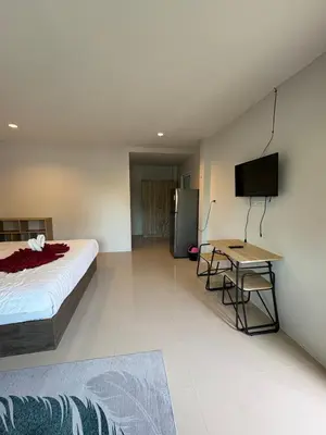 a bedroom with a bed and a table and a television at Cozy 1-Bedroom apartment in Surin Beach