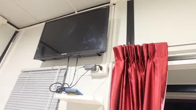 a flat screen tv hanging on a wall next to a window at Wings Alley Phuket in Phuket