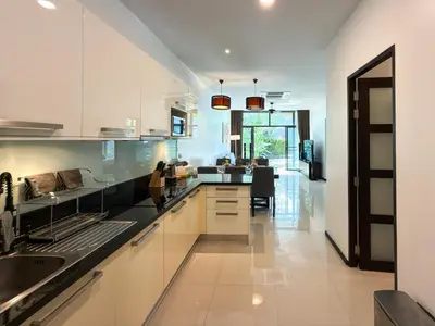 a kitchen with white cabinets and a dining room at Villa 2BD Nai Harn Beach by Mill in Ban Saiyuan (1)