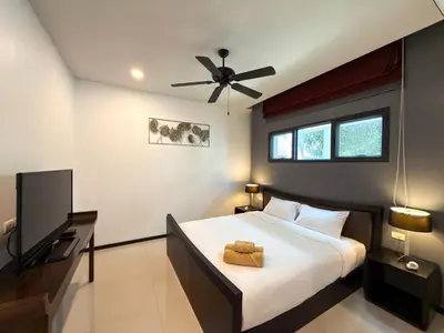 a bedroom with a bed and a flat screen tv at Villa 2BD Nai Harn Beach by Mill in Ban Saiyuan (1)