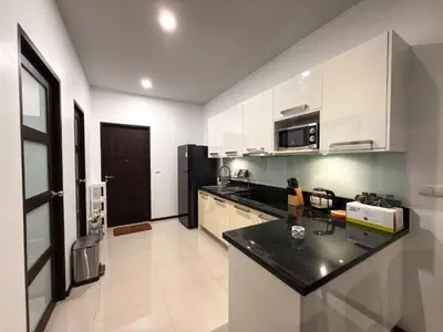 a kitchen with white cabinets and a black counter top at Villa 2BD Nai Harn Beach by Mill in Ban Saiyuan (1)