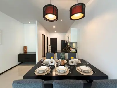 a dining room with a black table and chairs at Villa 2BD Nai Harn Beach by Mill in Ban Saiyuan (1)