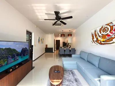 a living room with a blue couch and a flat screen tv at Villa 2BD Nai Harn Beach by Mill in Ban Saiyuan (1)
