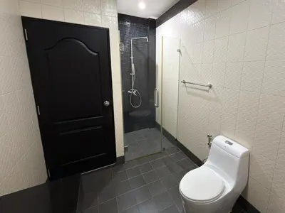 a bathroom with a toilet and a shower and a black door at Nai Harn Family Pool Villa 3 BDR by Mill in Ban Saiyuan (1)