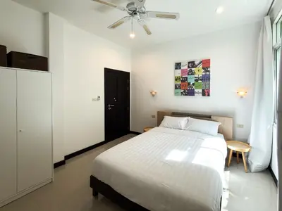a white bedroom with a bed and a ceiling fan at Nai Harn Family Pool Villa 4 bdr in Ban Saiyuan (1)