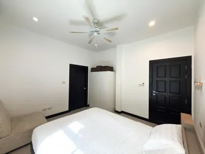 a bedroom with a bed and a ceiling fan at Nai Harn Family Pool Villa 4 bdr in Ban Saiyuan (1)