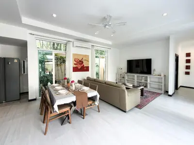 a living room with a table and a couch at Nai Harn Family Pool Villa 4 bdr in Ban Saiyuan (1)