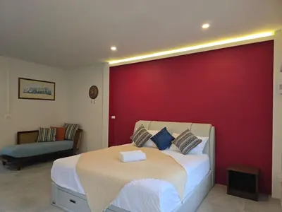 a bedroom with a bed and a red wall at The Simple Place - King in Klong Muang Beach