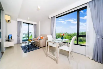 a living room with a table and chairs and a large window at AVN 1 BR Apt near beaches 15mn walk in Surin Beach