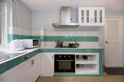 a kitchen with white cabinets and a black oven at Villa Hillside 2-story-3BR-Private Pool near Big Buddha in Ban Klang