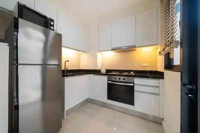 a kitchen with white cabinets and a stainless steel refrigerator at Happy 3 bedroom Townhouse Laguna Park in Laguna Phuket