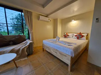 a bedroom with a bed and a couch and a window at The Cozy House in Karon Beach