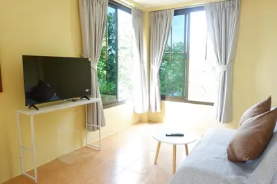a living room with a couch and a flat screen tv at The Cozy House in Karon Beach
