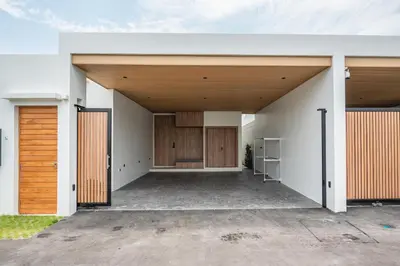 an open garage of a house with wooden doors at Mouana Residence Song Khun Chalong 4-bedroom Pool Villa 893 in Chalong